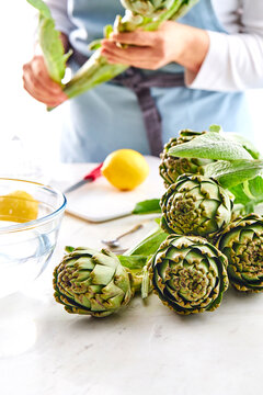Artichokes on a white kitchen background with a female figure in the distance