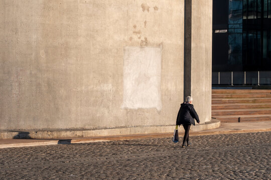 Minimalism street scene with pedestrian and walking silhouette near a wall of architecture in daylight urban Copenhagen Denmark expressing solitude and space