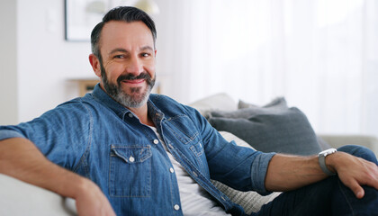 Fototapeta premium Smile, man and relax with portrait on sofa for peaceful morning, comfortable rest and free time. Space, mature person and happy in living room for weekend break, calm afternoon and unwind in house