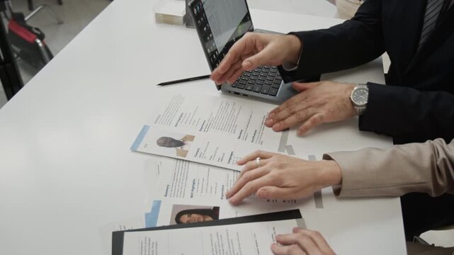 Zoom out view of two mature managers looking through applications forms while choosing right candidate for position during workday in modern office