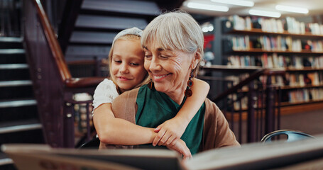 Book, hug and library with student and teacher on floor together for learning or literature. Development, education and reading with happy girl child embracing mature woman for growth in school