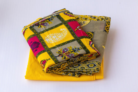 Yellow unstitched cotton three-piece fabric with ethnic block print patterns. Isolated on white background. Traditional South Asian salwar kameez and matching dupatta material