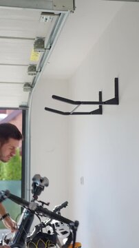 Man hanging bicycle on wall rack in garage. Concept of bicycle storage