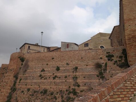 Mura fortificate in mattoni con edifici storici, architettura medievale italiana
