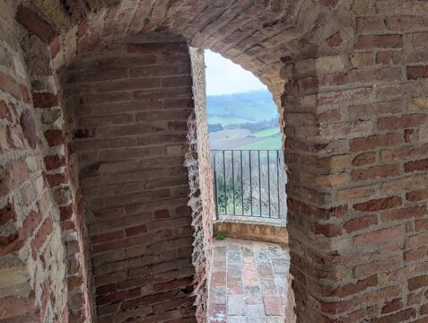 Passaggio in mattoni con arco su terrazza panoramica, architettura medievale italiana affacciata sulle colline