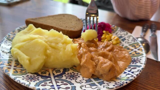 Lunch, mashed potatoes, herbed chicken, black bread, pickled cabbage with beets on a blue and white plate, corn. High quality 4k footage
