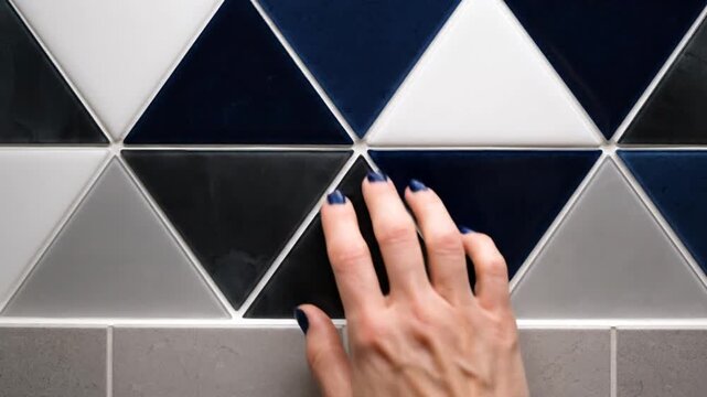 Hand Touching Geometric Tiled Wall Surface.