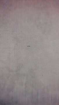 Close-up shot of a red computer screen with a grid-like pattern of small black dots against a solid black background.