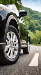 A car's rear wheel rests on an asphalt road in a forest on a summer day, showing a journey through nature with clear space for text