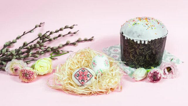 Painted Easter eggs arrive cyclically near willow branches and Easter cupcake. Light pink background. Looping stop motion animation. Copy space.