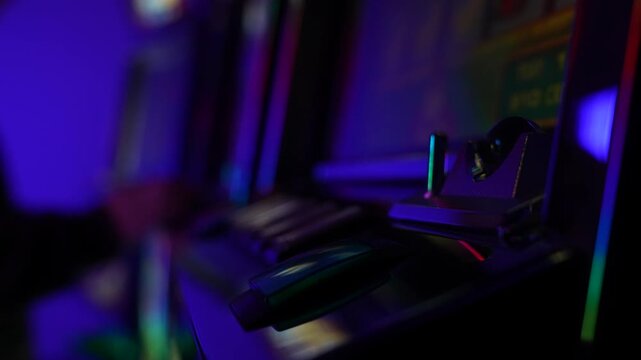 A close up of the green START button on a casino slot machine control panel. In the background is a blurred silhouette of a man playing the machine, frustrated by his loss.