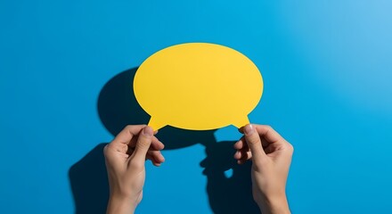 Obraz premium Human hands gracefully presenting a bright yellow blank speech bubble, set against a striking blue background, perfect for conveying messages, opinions, and interactive dialogue