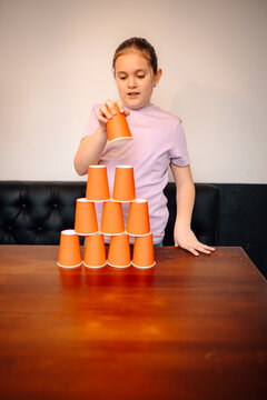 Child stacking paper cups building a pyramid