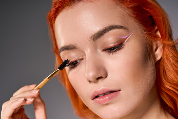 Obraz premium Stylish young woman applying makeup with passion and creativity in a vibrant setting