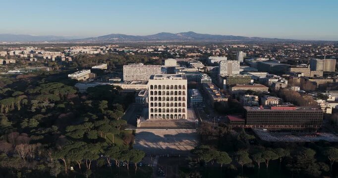 Aerial view of the Palazzo della Civilta Italiana, a stark white architectural marvel, contrasting with the surrounding lush green trees, Rome, Lazio, Italy.