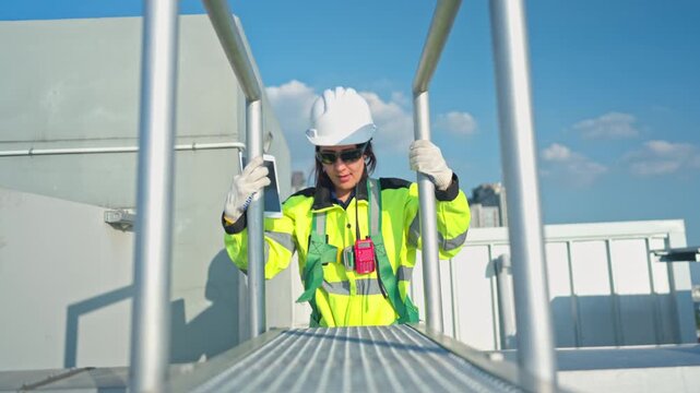 Young woman engineer climbing a metal ladder to inspect industrial equipment, emphasizing safety standards and maintenance operations