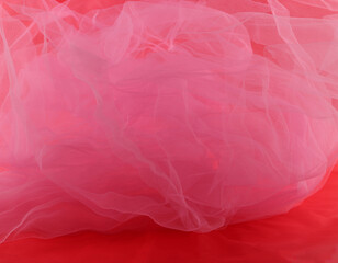 Fototapeta premium Pink tulle fabric on red background. Abstract transparent material curve wave.