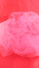 Pink tulle fabric on red background.  Abstract transparent material curve wave.