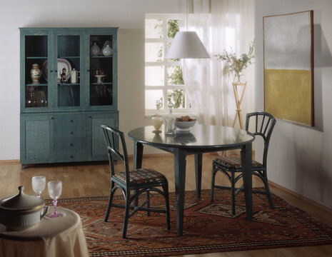 Single shot photo of a room with a rattan table, chairs and display cabinet