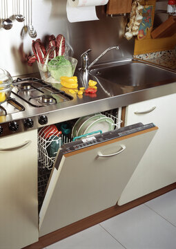 Close up of a steel kitchen counter with an open dishwasher