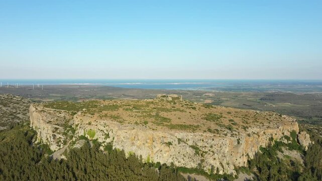 Drone shot of the rocky plateau and surrounding landscape at Chateau de Opoul Perillos in southern France, with distant views of the Mediterranean coast.