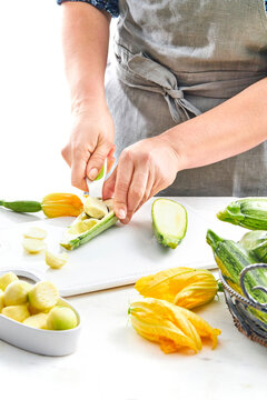 woman hands scooping out the flesh of a zucchini in a kitchen setting