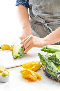 woman hands cutting a zucchini in half with a knife in a kitchen setting