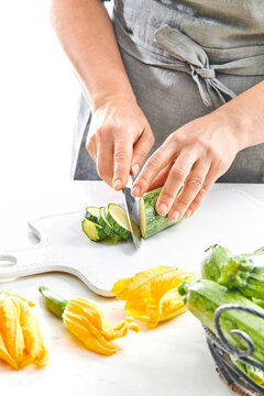 woman hands slicing a zucchini with a knife in a kitchen setting