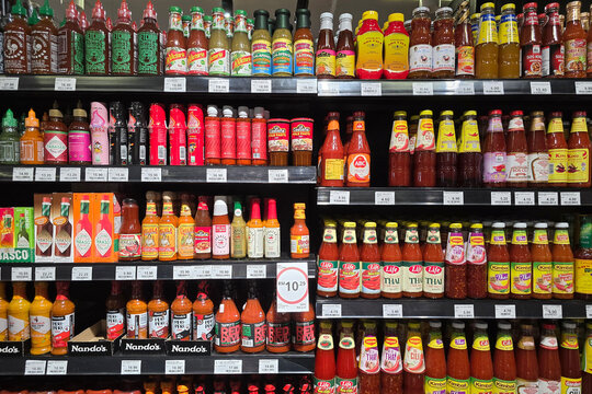 Penang, Malaysia: Nov 06, 2025: A retail display featuring a wide variety hot sauces, including brands like Tabasco, Nando's Peri-Peri, Cholula, ABC, and Maggi, arranged on grocery store shelves.