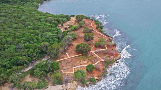 High altitude drone view of La Isabela historical park surrounded by dense forest and the Caribbean Sea in Dominican Republic