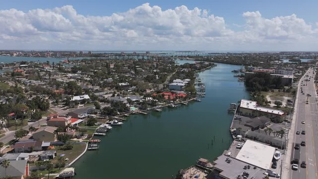 Aerial view of Belle Vista coastal neighborhood in Saint Pete Beach showcasing waterfront homes with private docks, swimming pools, and Pinellas Bayway bridge across Boca Ciega Bay, Florida.
