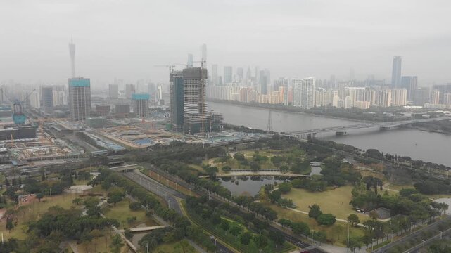 Drone shot of a construction site and skyline of Guangzhou on a grey smoggy day
