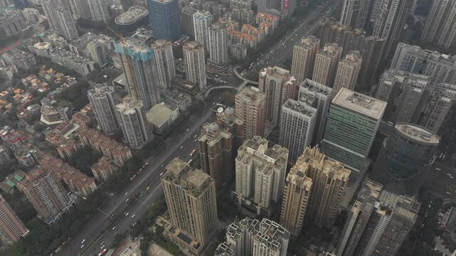 Tilting drone shot of traffic driving through dense residential and commercial neighborhood in downtown Guangzhou, China's third largest city