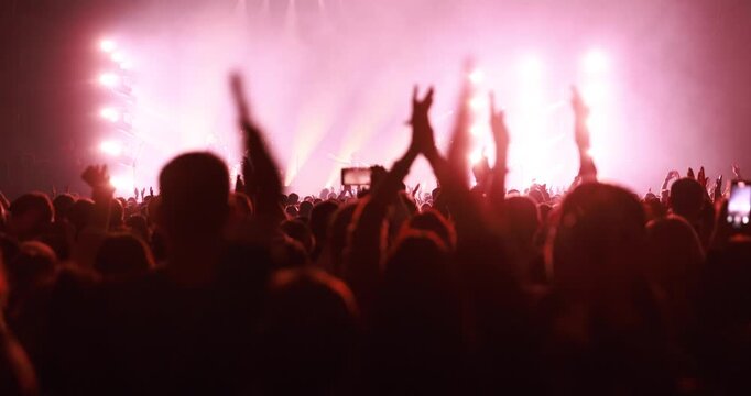 Hands are seen clapping rhythmically against the backdrop of a brightly lit stage during a live show. The audience expresses enthusiasm and support.