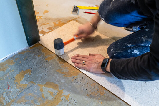worker glues cork tiles with plastic hammer