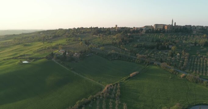 Classic Tuscany landscape with green hills and farmland country at sunrise. Aerial shot of green spring fields and hills in Tuscany, Italy