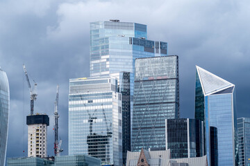 Naklejka premium Modern glass skyscrapers in the London financial district rise across the River Thames representing contemporary urban architecture and a dynamic business city skyline.