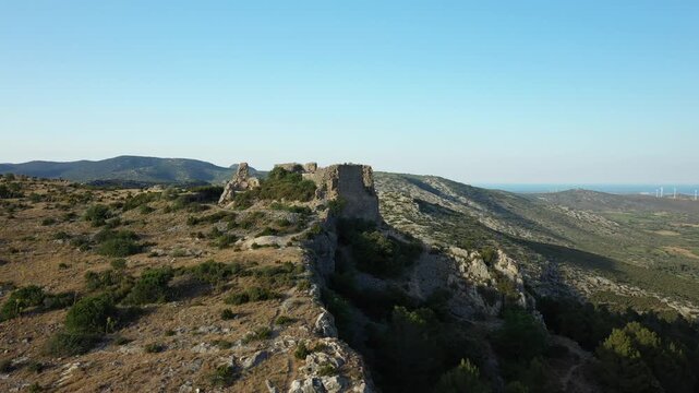 Aerial view of the historic ruins of Chateau de Opoul Perillos set atop a rugged hill with expansive mountain landscape in southern France.