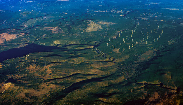 Bird's eye view of wind turbines farm in mountain range.