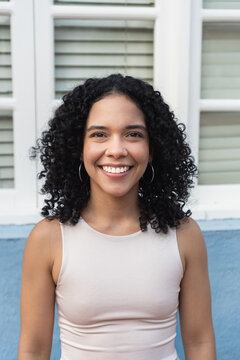 Young woman with curly hair smiling outdoors