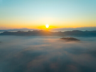 Naklejka premium Aerial view of flowing fog waves on mountain tropical rainforest,Bird eye view image over the clouds Amazing nature background with clouds and mountain peaks in Thailand