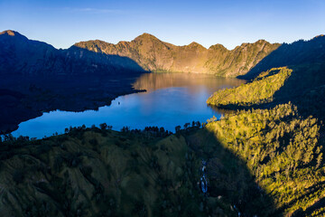 Naklejka premium Majestic sunrise illuminating the steep ridges of Mount Rinjani and Segara Anak lake