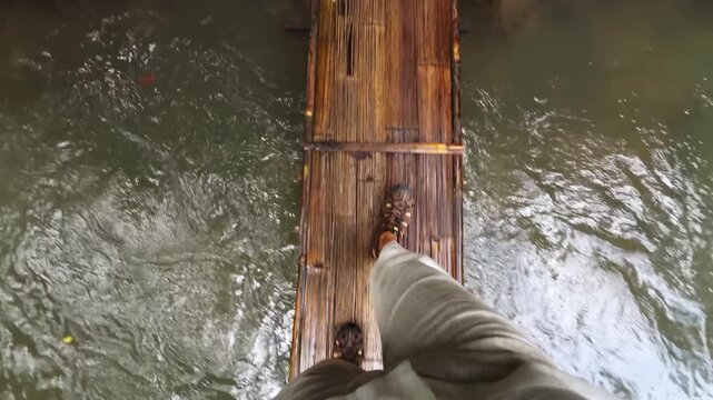 Man in flip-flops crossing a bridge over the river
