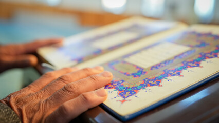 Fototapeta premium A Muslim sheikh reading the Qur’an in the mihrab of the mosque, an elderly Muslim man praying during Ramadan. Concept of religions, Eid al-Fitr.
