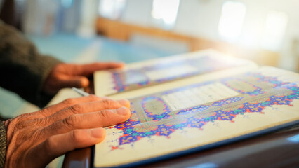 Fototapeta premium A Muslim sheikh reading the Qur’an in the mihrab of the mosque, an elderly Muslim man praying during Ramadan. Concept of religions, Eid al-Fitr.