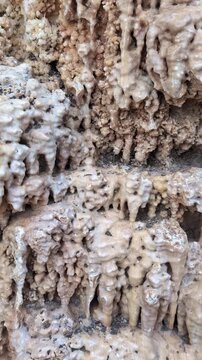 Natural mineral cave formations texture : Close up geological surface showing dripping calcite deposits and rough limestone structure formed over time in underground environment.