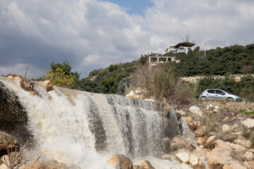 an exuberant waterfall, a car, and rural houses.