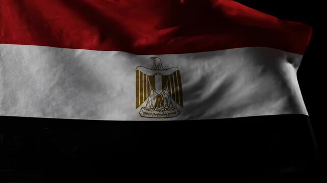 Close-up view of the national flag of Egypt, featuring its red, white, and black stripes with the golden Eagle of Saladin emblem.