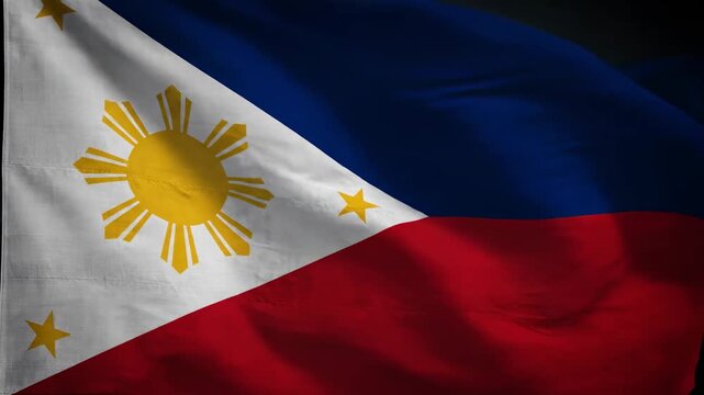 Close up the national flag of the Philippines waving gently, showcasing its vibrant blue, red, and white colors with the golden sun and three stars.