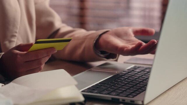 Close up female hand holding credit blocked bank card typing laptop problem unrecognizable Caucasian business woman girl paying online internet banking fail debt error computer unknown businesswoman